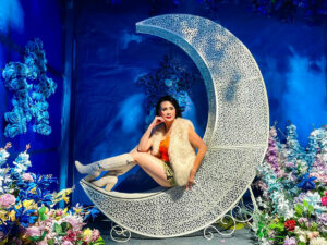 Woman sitting on a chair shaped like a moon in a large photo booth