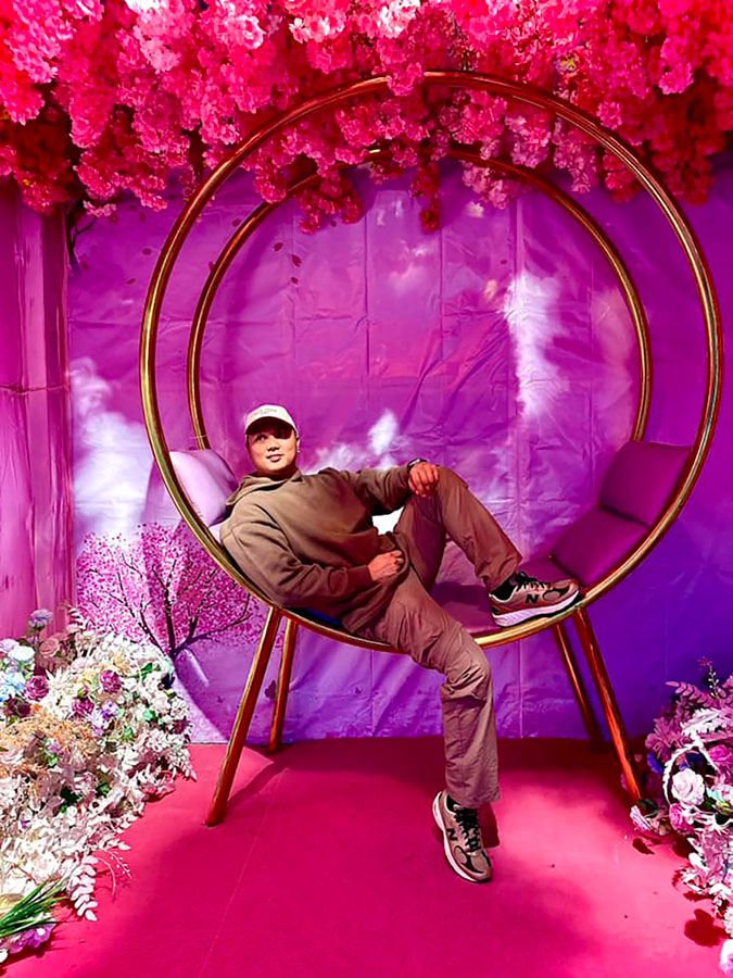 Man sitting in a gold circular chair in large photo booth
