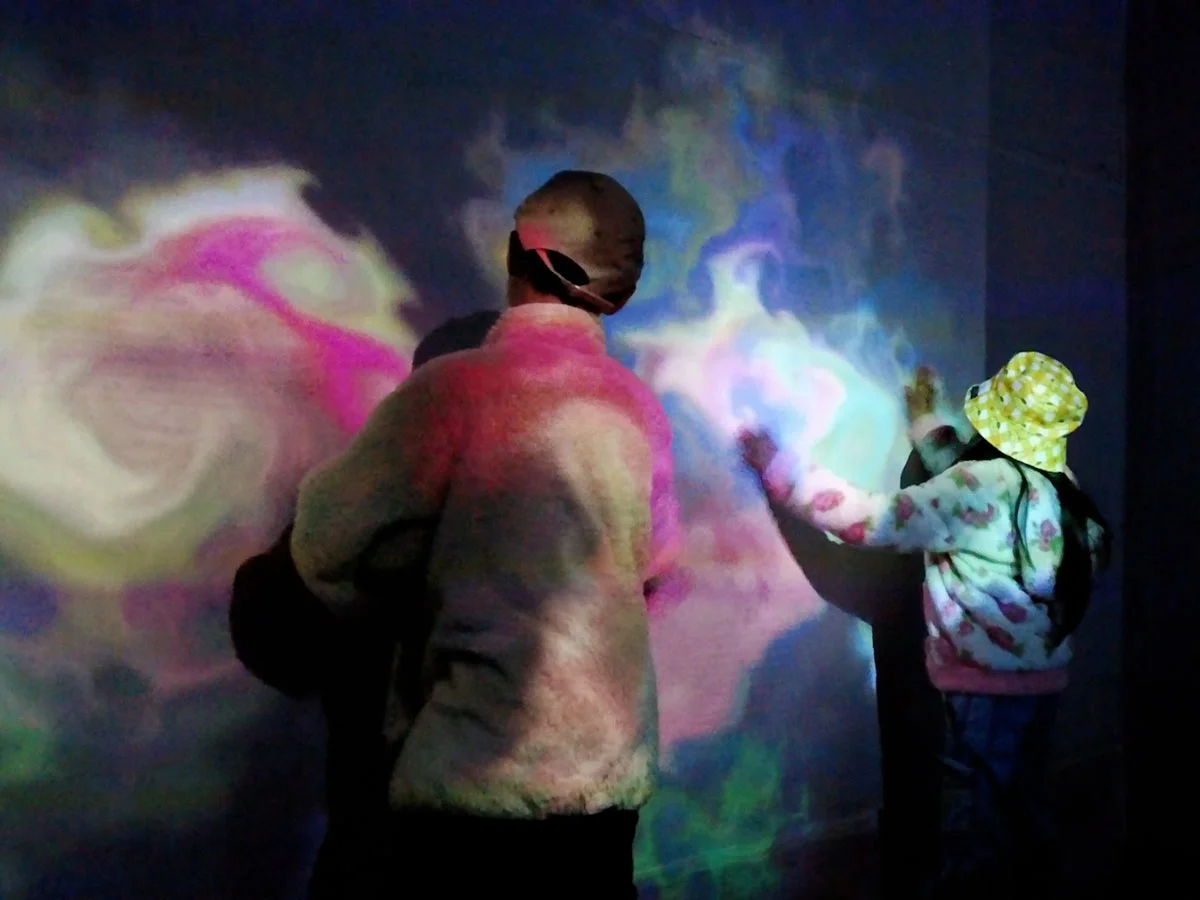 Two people interact with the wall in an interactive activity room.