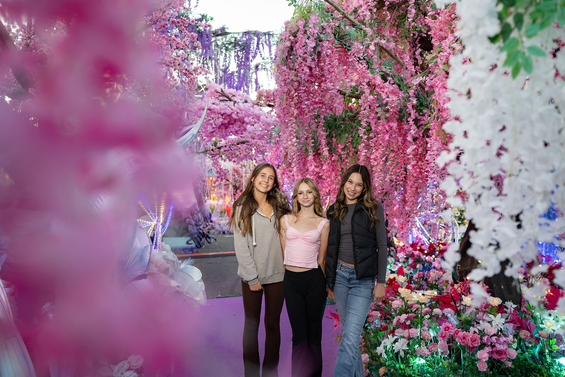 Three teenage girls posing for a photo surrounded by flowers