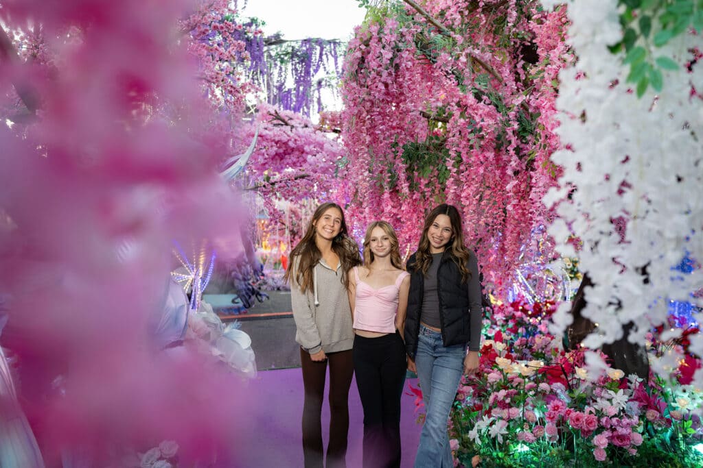 Three teenage girls posing for a photo surrounded by flowers