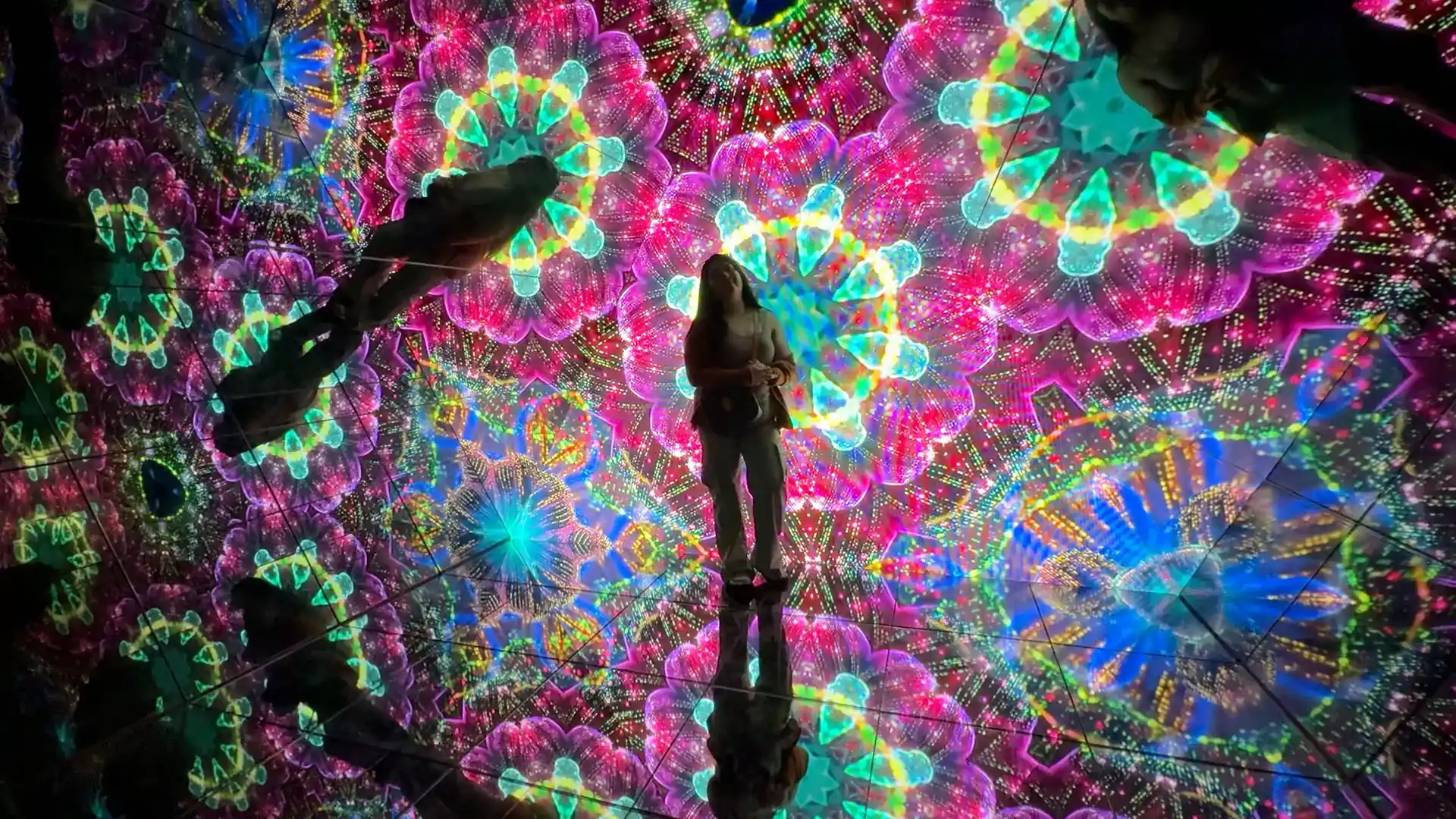 A child looks around in a colorful mirror room.