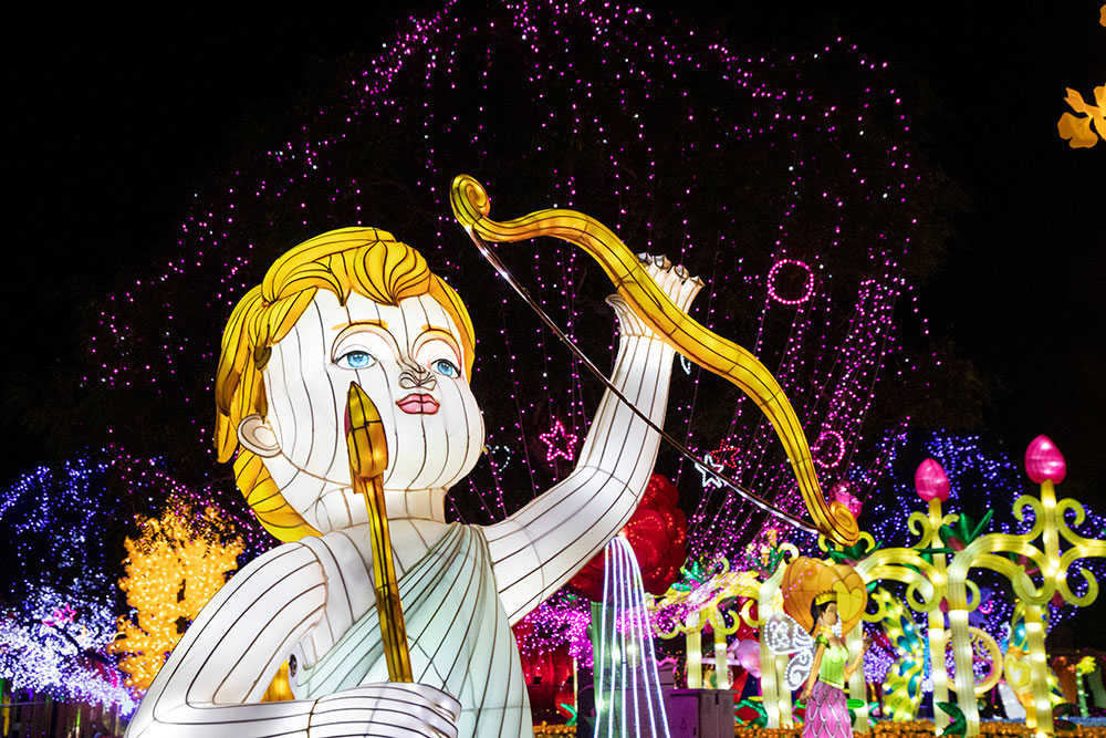 Giant lit structure of cupid holding a bow and arrow.