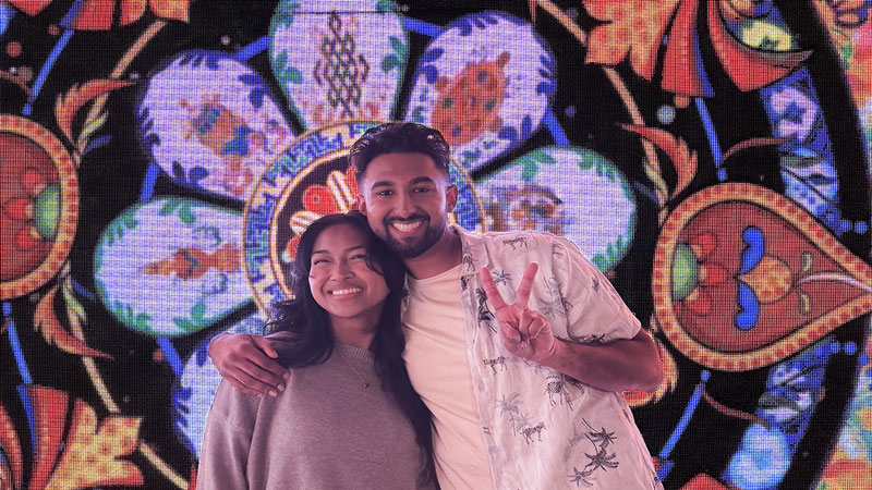 East Asian Man giving a Peace sign smiling with his arm around an Ethnically Ambiguous Woman in an Infinity Mirror Room at Imaginarium