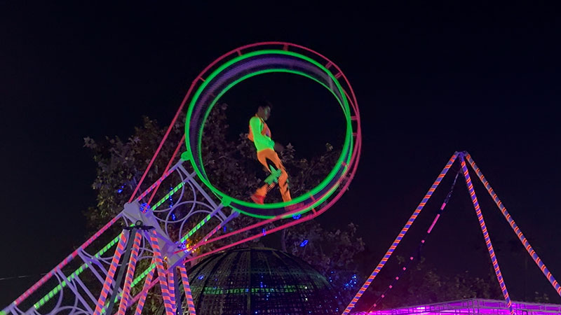 Imaginarium Let's Glow Crazy – The Neon Circus, a circus performer performs in the double wheel of destiny.